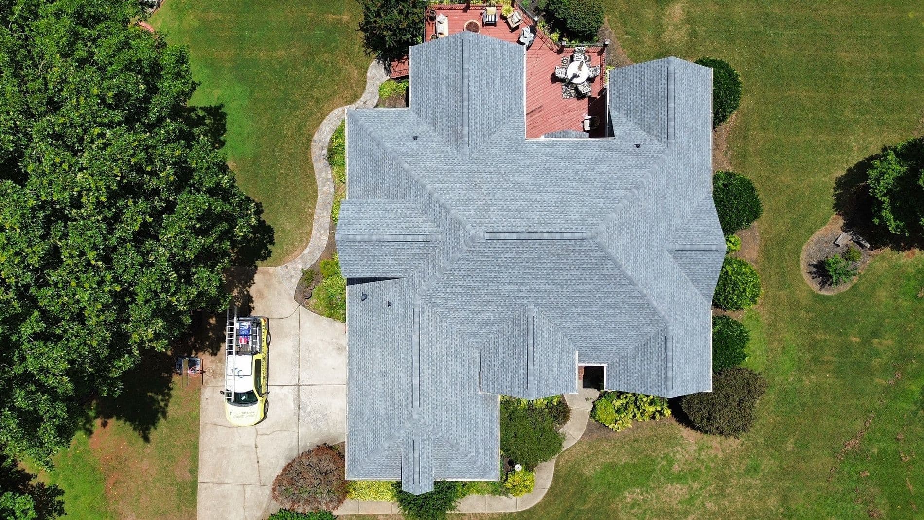 An overhead aerial view of a house with newly-installed light gray asphalt shingle roofing.